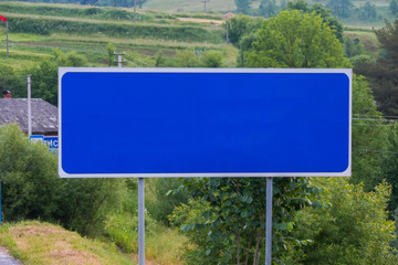 blue road sign before the city on the road without naming it