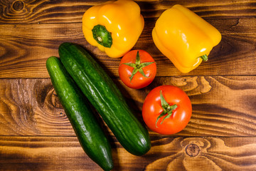 Cucumbers, tomatoes and sweet pepper on wooden table. Top view