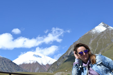 Portrait of woman in sunglasses looking at camera on mountains at background, Kazbegi, Georgia