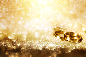 Wedding rings on festive golden background