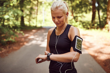 Fit woman setting her sports watch before a forest run