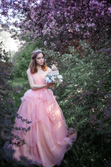 Obraz na płótnie Canvas girl in a pink dress in a flower garden