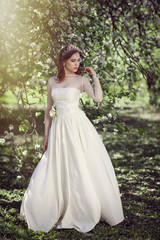 Obraz na płótnie Canvas Beautiful young bride in a blooming garden