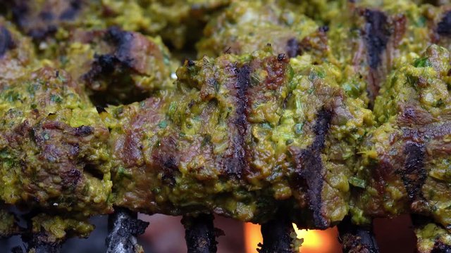 Extreme closeup of a piece of marinated meat on a hot grill with fire and burn marks.
