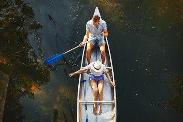Young couple paddling their canoe on a lake in summer