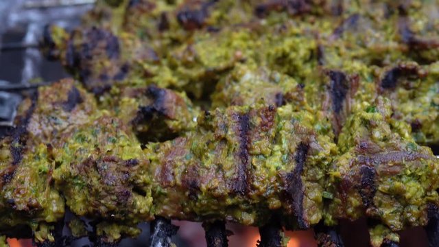 Extreme closeup of shish kabobs on a grill with fire beneath them.