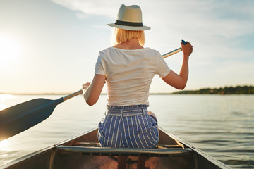 Young woman canoeing on a still lake in the summer
