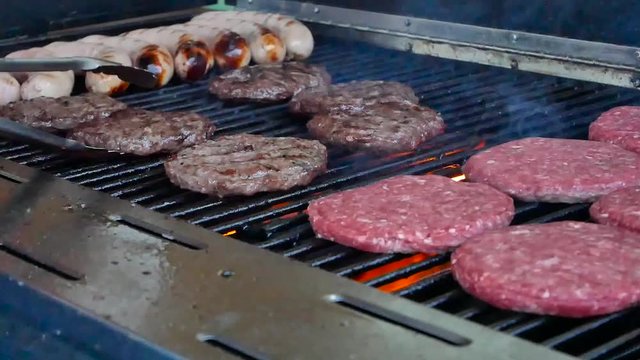 Grilling burgers and sausages on the grill over fire, Manchester UK