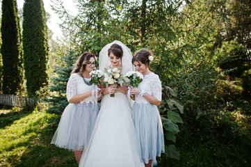 Happy bride posing with her bridesmaids outdoor with bouquets.