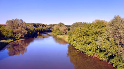 The blue river, on the banks grow trees.
