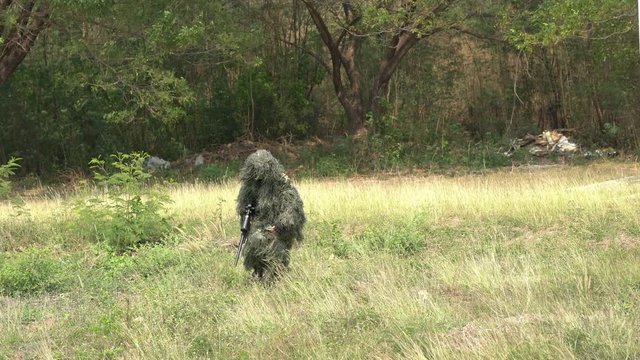 Sniper soldier lying on the ground and camouflage in grass. Soldier holding gun weapon and waring armor uniform. The military is responsible for maintaining the territory.