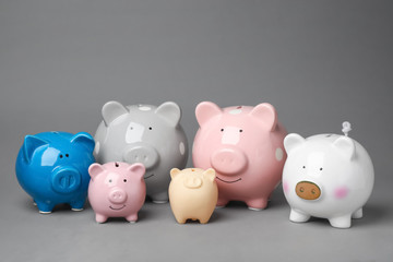Different cute piggy banks on gray background