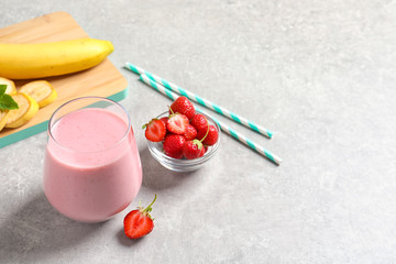 Glass with tasty strawberry smoothie on table