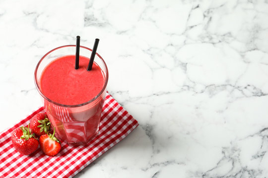 Glass with tasty strawberry smoothie on marble table
