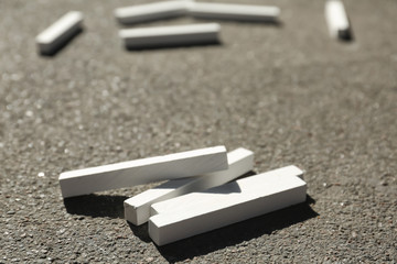 Many white chalk sticks on asphalt, closeup