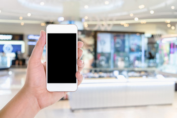 A man hand holding smart phone device wih blank copy space screen  in a department store or shopping mall