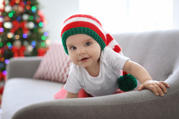 Cute baby in Christmas costume on sofa at home