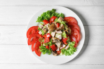 Plate with delicious fresh salad on table, top view