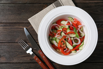 Plate with delicious fresh salad on table, top view
