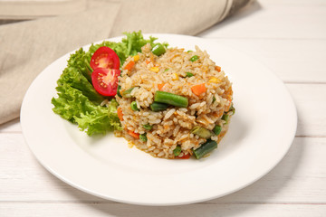 Plate with tasty boiled rice and vegetables on table