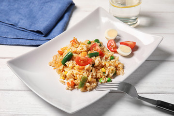 Plate with tasty boiled rice and vegetables on table