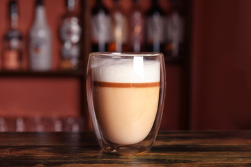 Glass with delicious latte on counter in bar