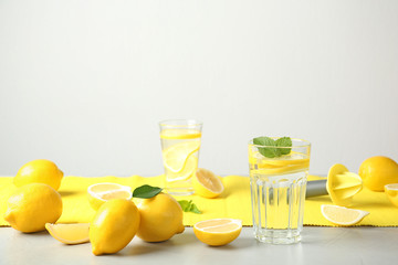 Glass with lemon water and fresh fruits on table