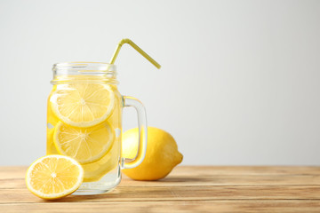 Mason jar with lemon water and fresh fruit on wooden table