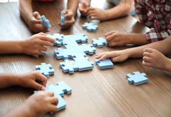 Little children playing with puzzle at table, focus on hands. Unity concept