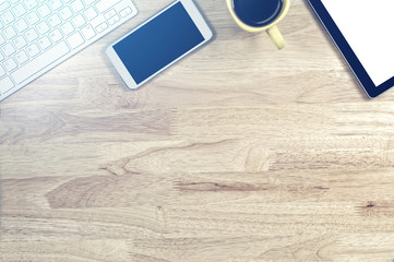 blank screen smartphones and tablet PC on the wooden desktop with computer keyboard and a cup of coffee in composition with copy space for your text