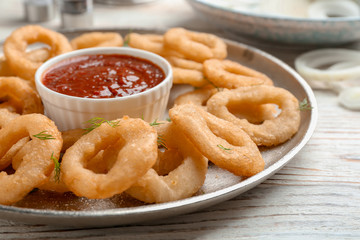 Fried onion rings served with sauce on plate, closeup