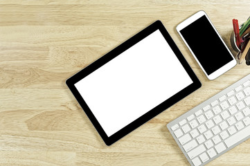 blank screen smartphones and tablet PC on the wooden desktop with computer keyboard and a cup of coffee in composition with copy space for your text