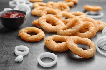Raw and fried onion rings on table, closeup