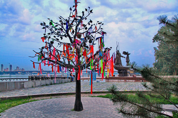 A tree with multi-colored ribbons is a symbol of a happy family on the background of the famous monument on the embankment.