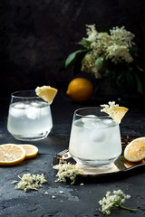 Two glasses of homemade elderflower gin sour or lemonade garnished with freshly picked elderflowers.
