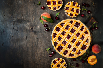 Homemade cherry pie on rustic background with cherries and peaches