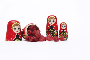 Traditional wooden doll's Matreshka Babushka with raspberries isolated on a white background