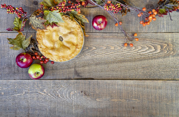 Delicious home baked apple pie on rustic autumn background with apples, berries and leaves