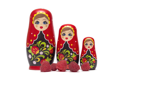 Traditional wooden doll's Matreshka Babushka with raspberries isolated on a white background