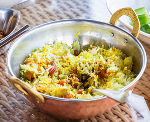 Closeup spicy and delicious chicken biryani served with sauce raita and achar. Served in authentic indian copper utensils.