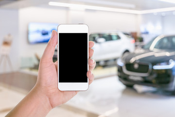 man hand using mobile smart phone with blank screen in a blurred background of car showroom
