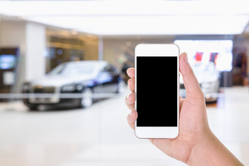 man hand using mobile smart phone with blank screen in a blurred background of car showroom