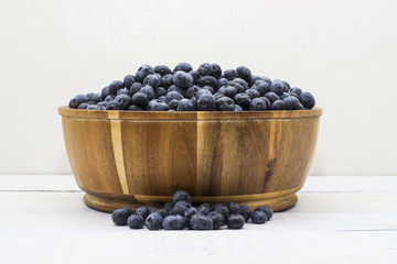 Close up of a wooden bowl full of farm fresh blueberries