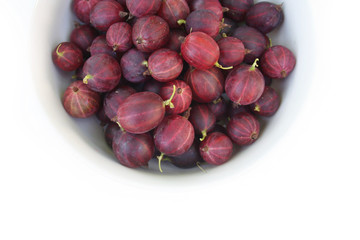 Ripe red gooseberries in a bowl isolated on white background