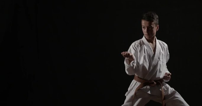 Young Karateka practicing kata on black  50fps