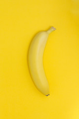 Creative view of a banana on a paper yellow background.