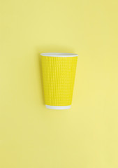 Abstract view of a paper cup for coffee. Yellow background.