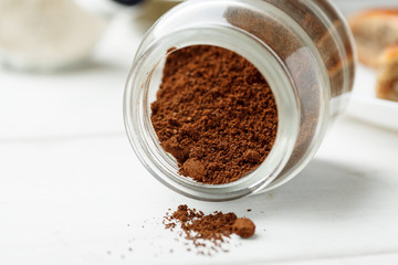 Ground natural coffee in glass jar on a white table