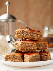 Oriental sweets with walnut in a white plate on a wooden table, vertical