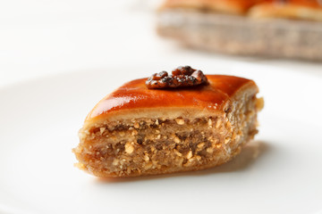 Oriental sweets with walnut in a white plate on a wooden table, closeup